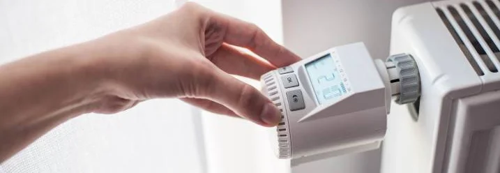 Hand stellt Heizkörperthermostat ein